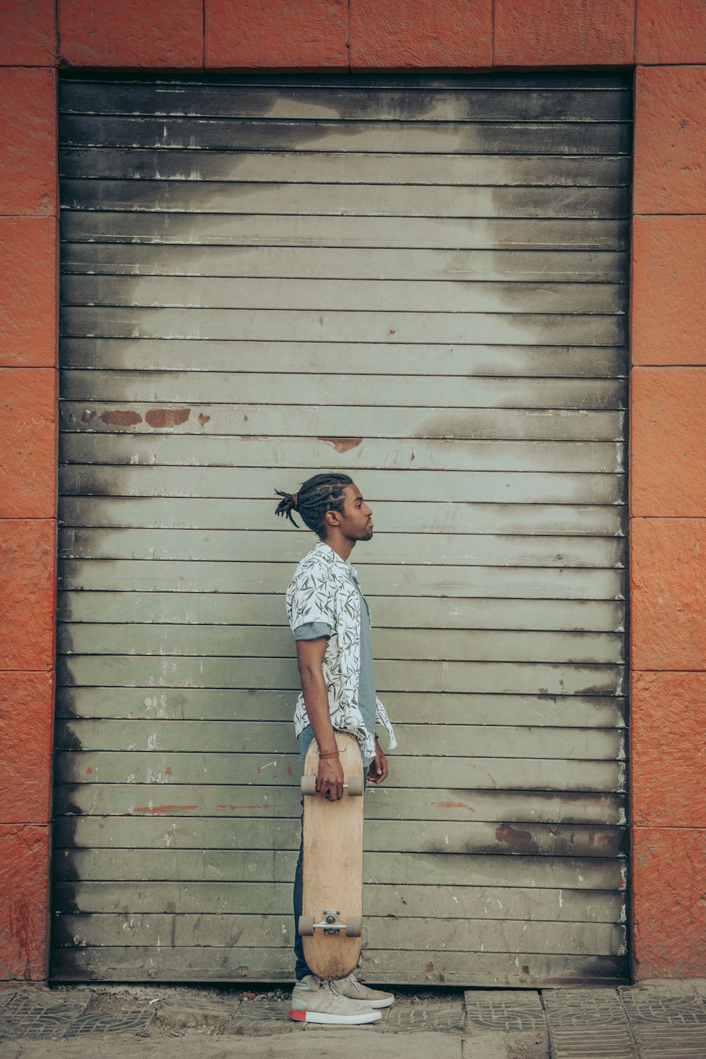 a man holding a skateboard in front of a garage door