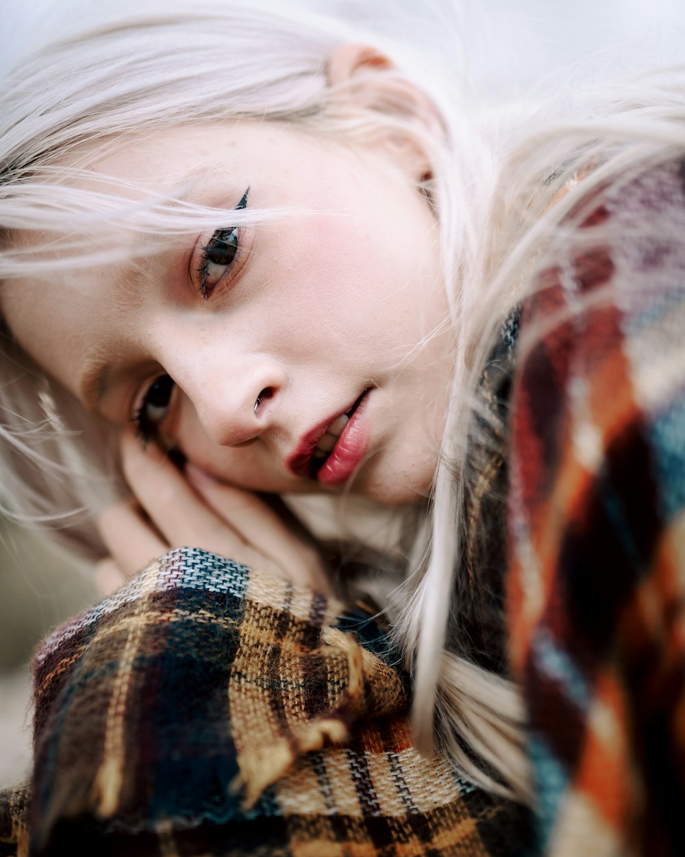 a woman with white hair and a plaid coat