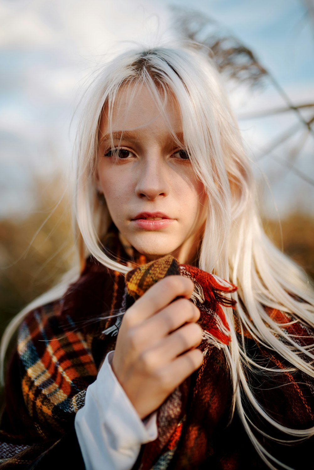 a woman with long white hair wearing a plaid scarf