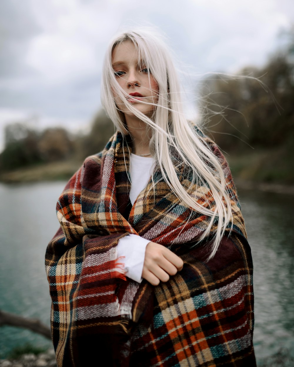 a woman with white hair is wrapped in a plaid blanket