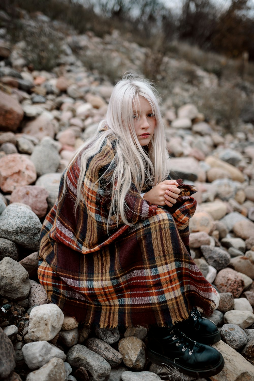 a woman with white hair sitting on rocks