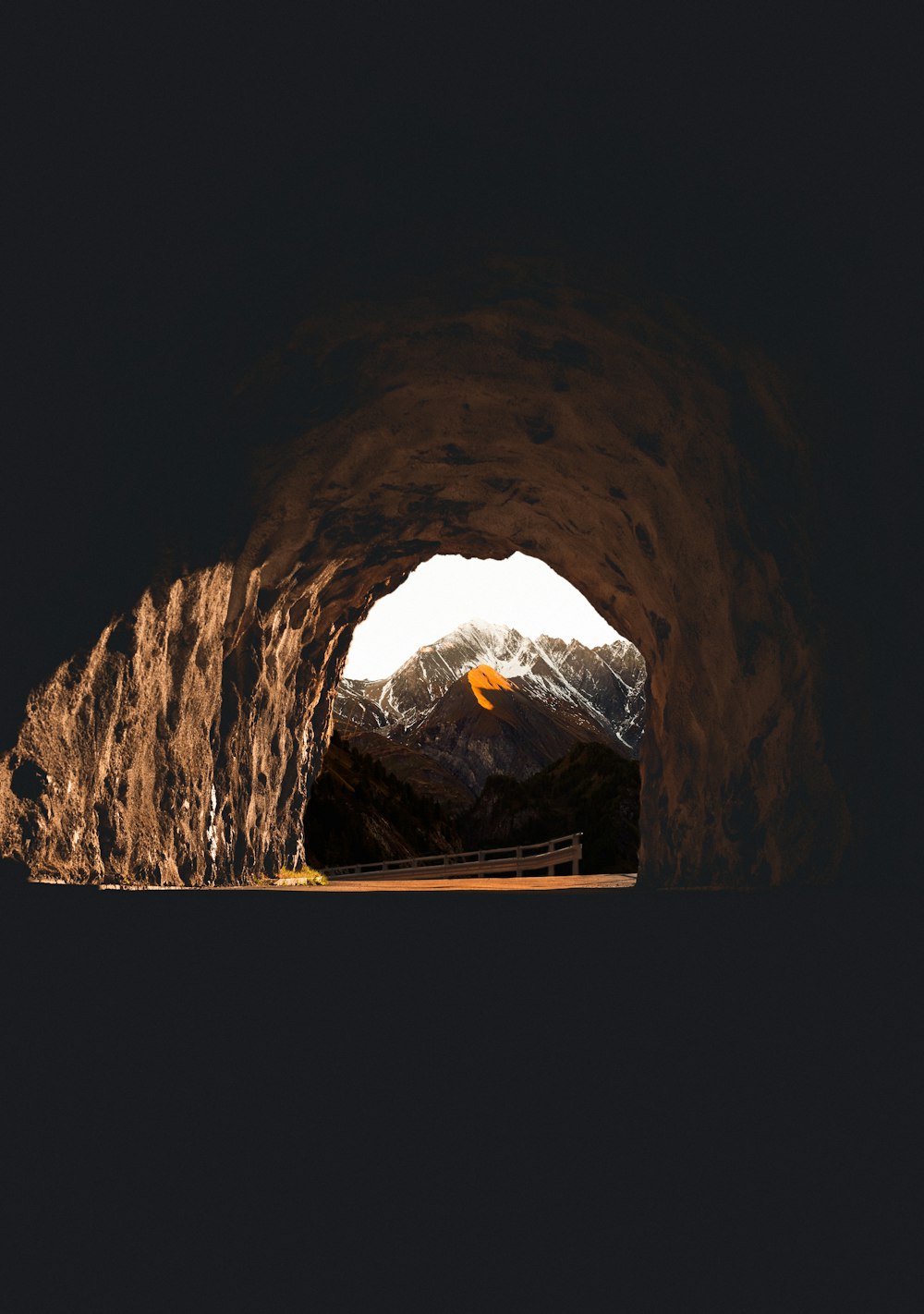 a dark tunnel with a mountain in the background