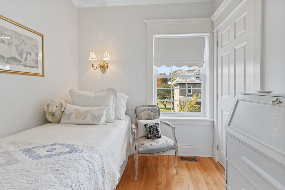 a bedroom with a white bed and a chair