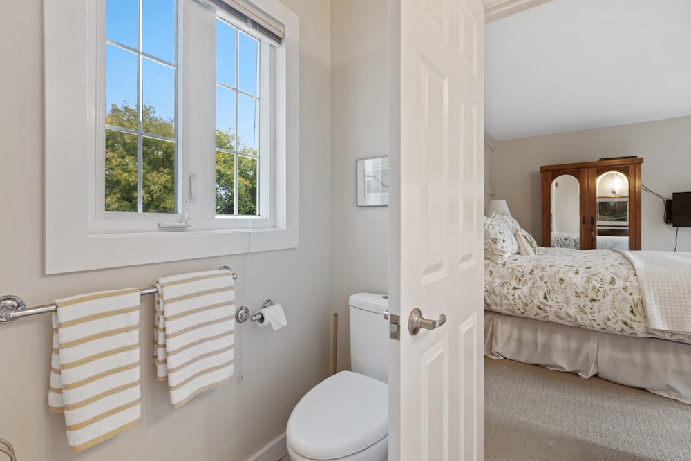 a white toilet sitting next to a window in a bathroom