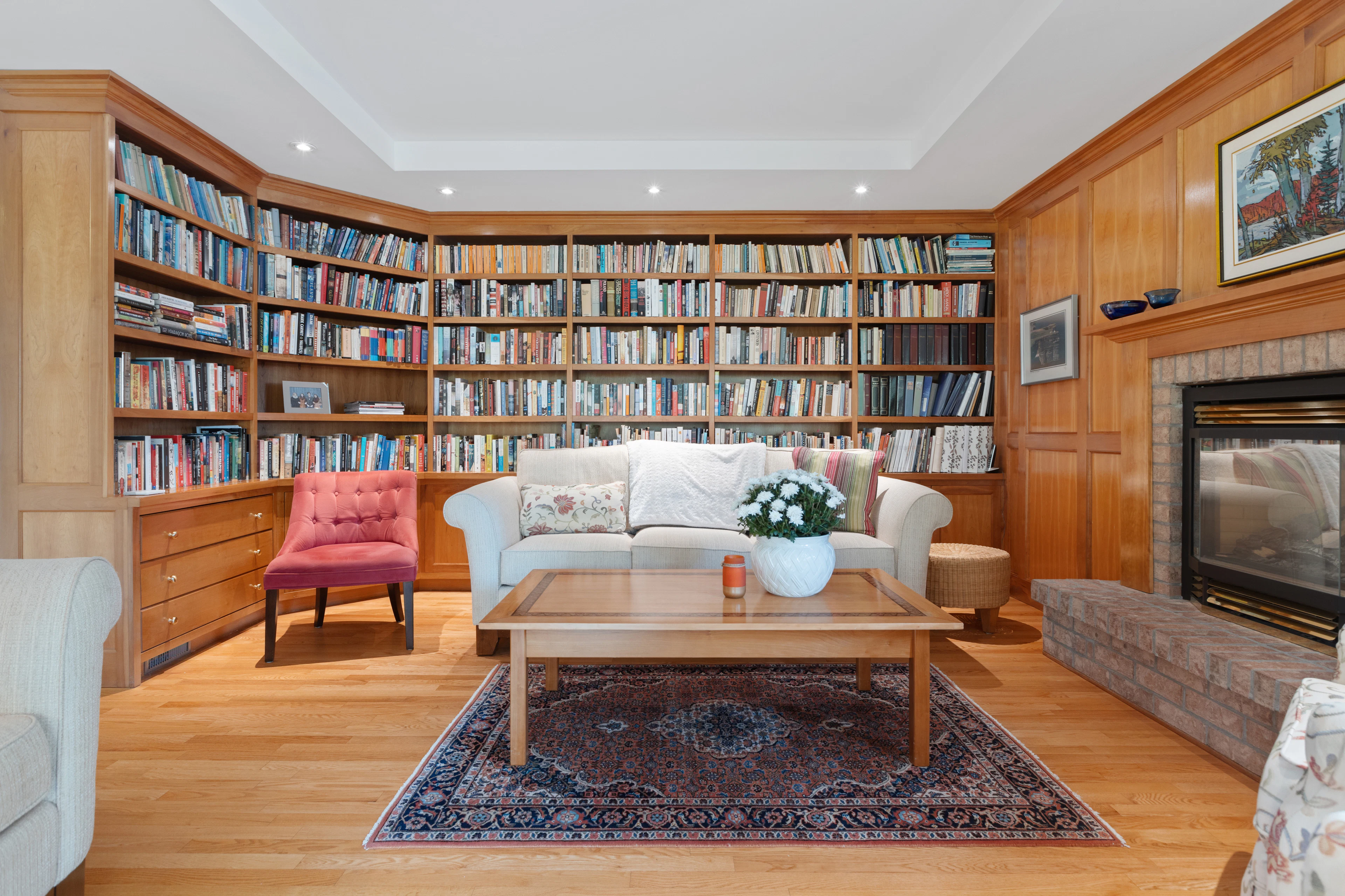 Wood-paneled living room library with built-in shelving and fireplace