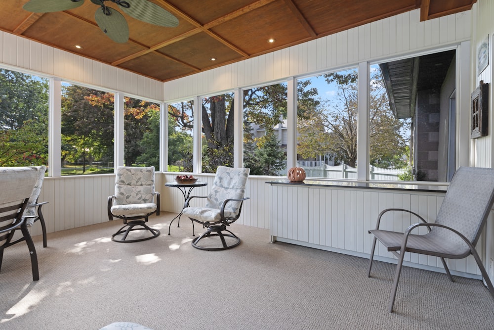 a screened porch with chairs and a table