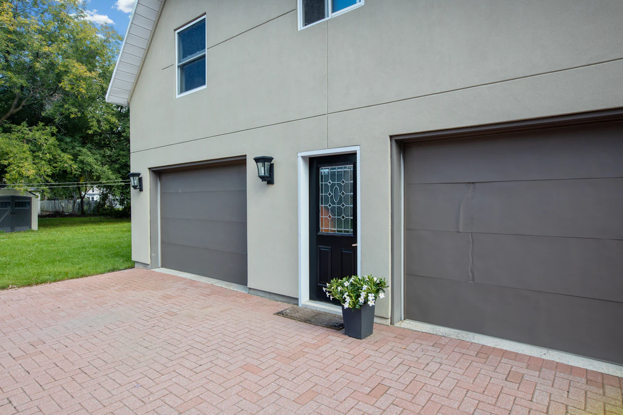 Two brown panel garage doors beside a front entry