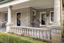 a front porch with columns and a grill