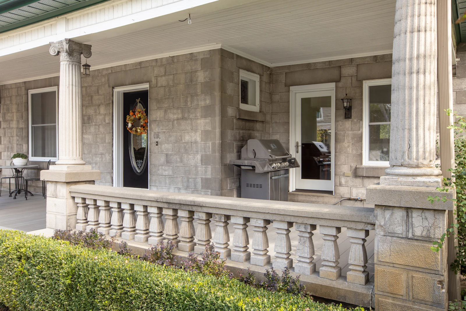 Grey house with a columned front porch and manicured lawn, an example of strong curb appeal