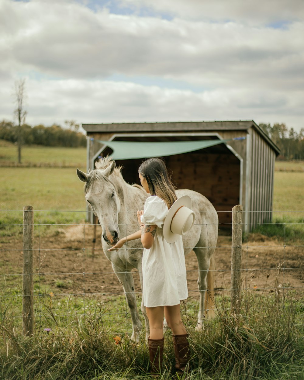 a woman standing next to a horse in a field