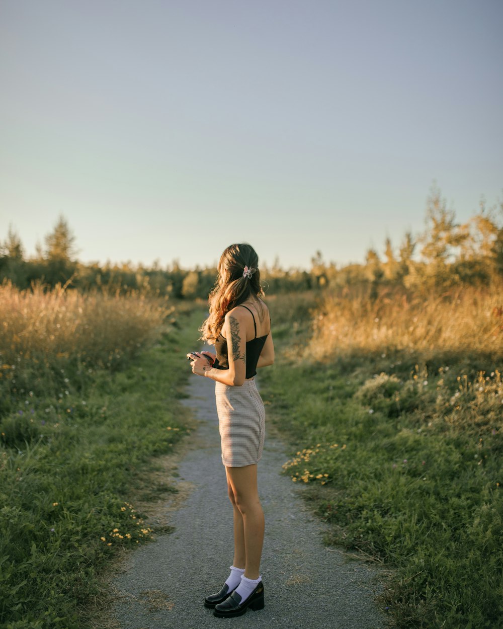 a woman standing on a path in a field