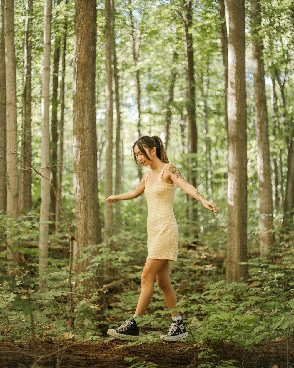 a woman in a yellow dress walking through a forest