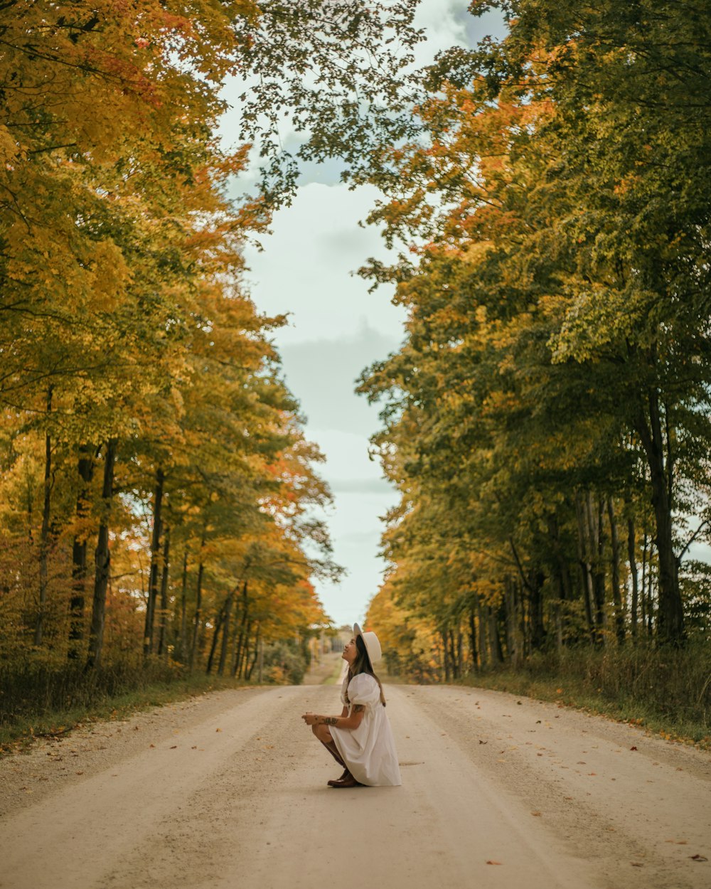 a woman sitting on the side of a dirt road