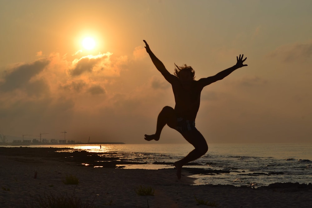 a person jumping in the air on a beach