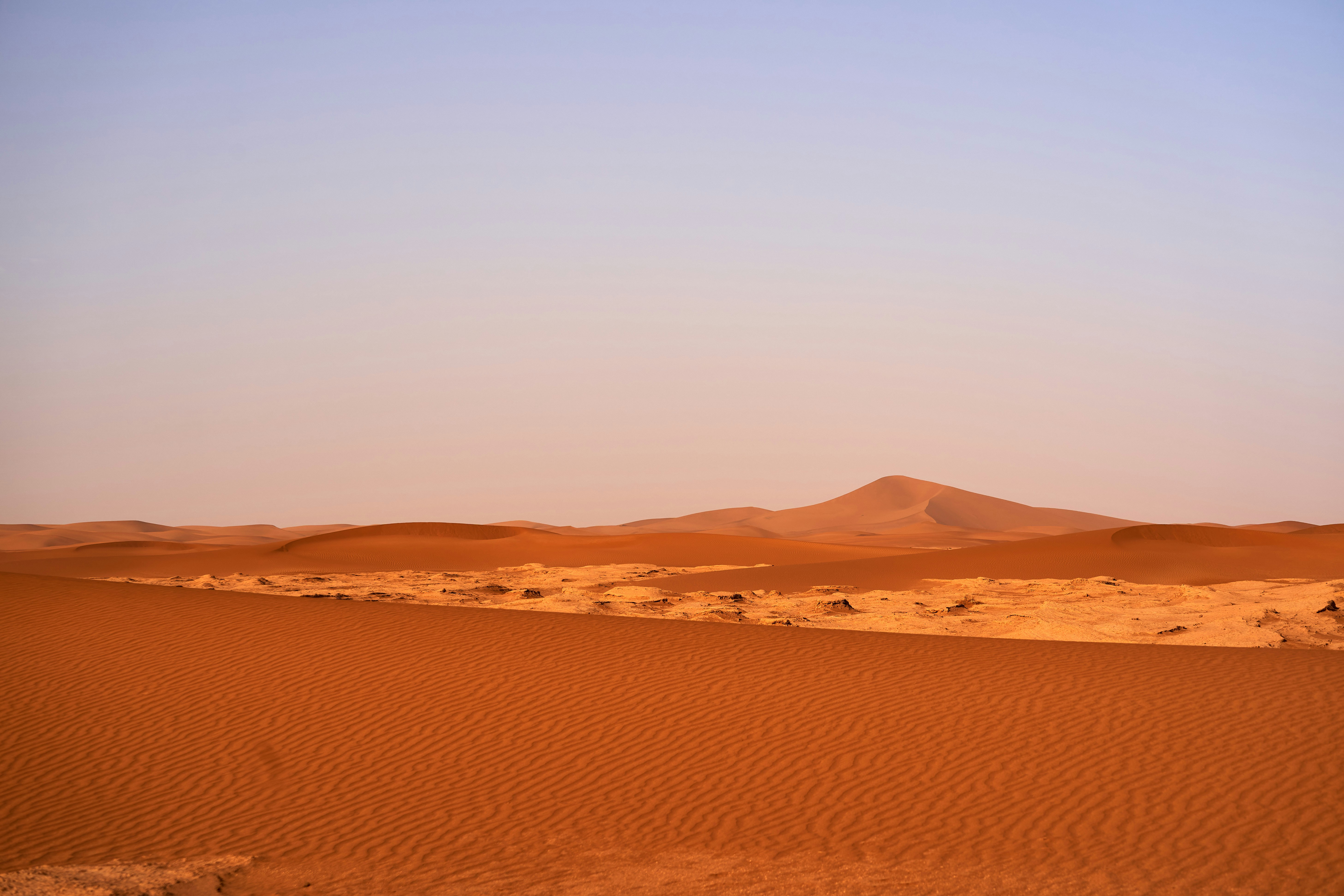 A desert landscape with sand dunes and a blue sky