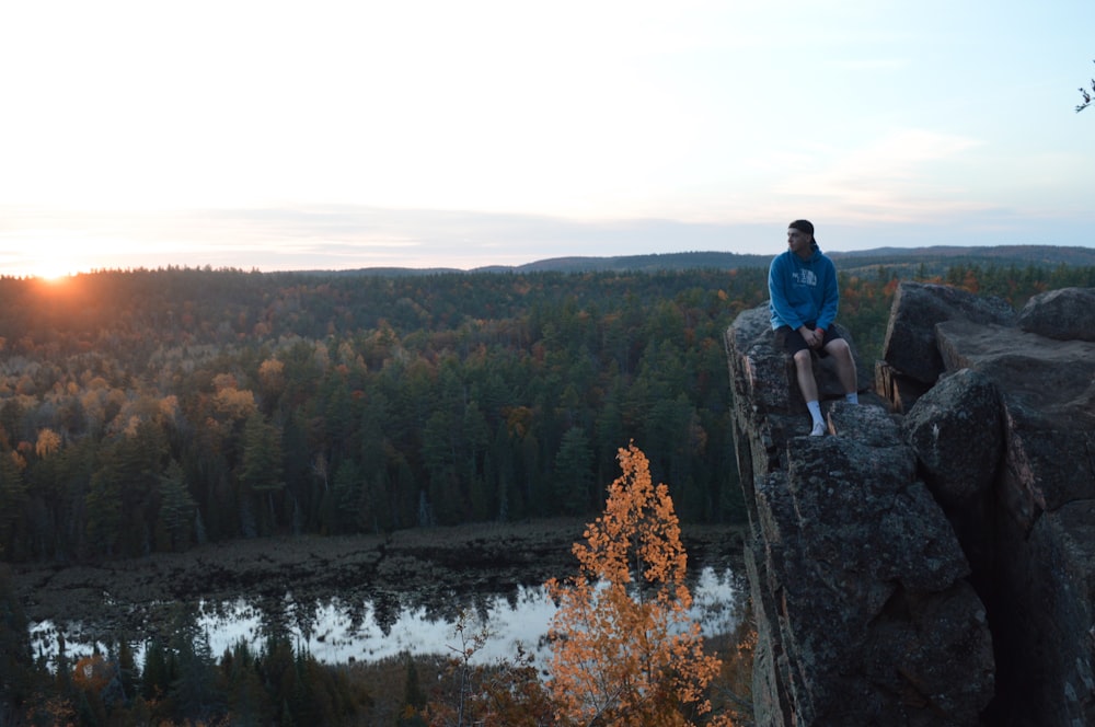 a person sitting on a rock overlooking a lake