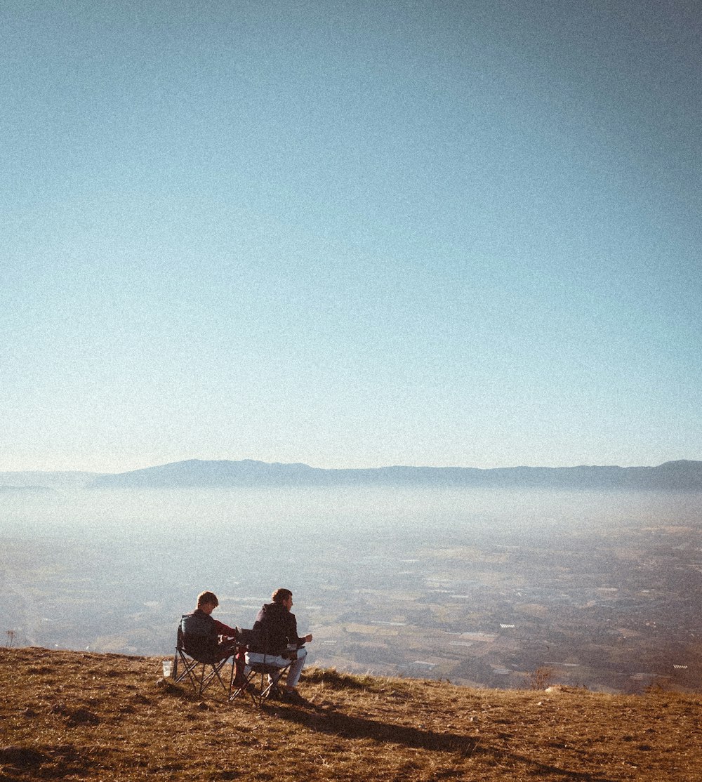 Un par de personas sentadas en la cima de una colina