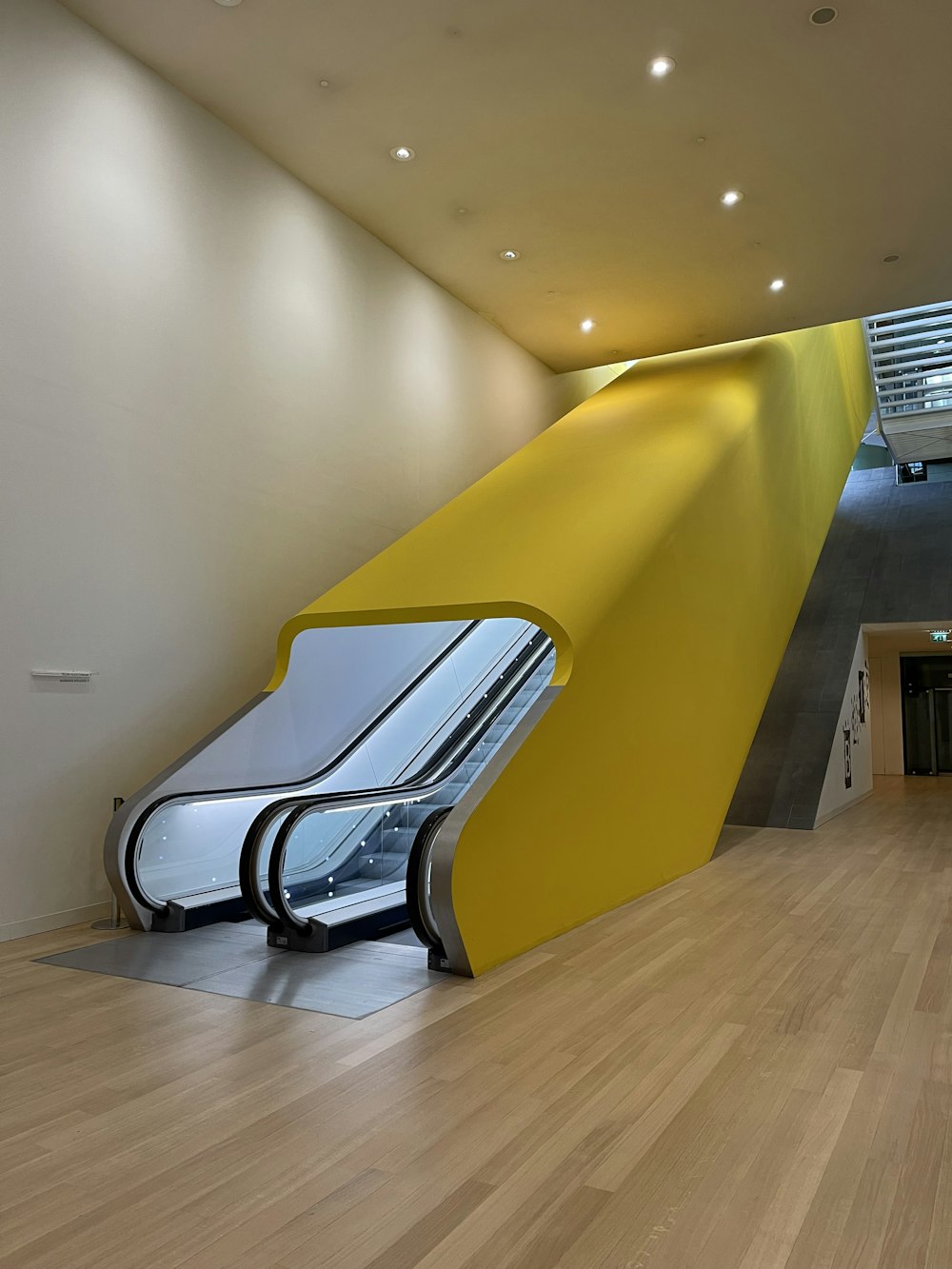 an escalator in a building with a yellow wall