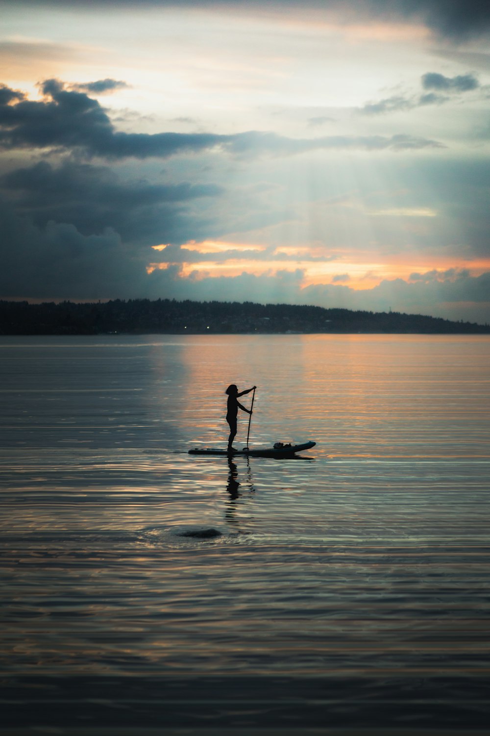 una persona montando una tabla de paddle en un cuerpo de agua