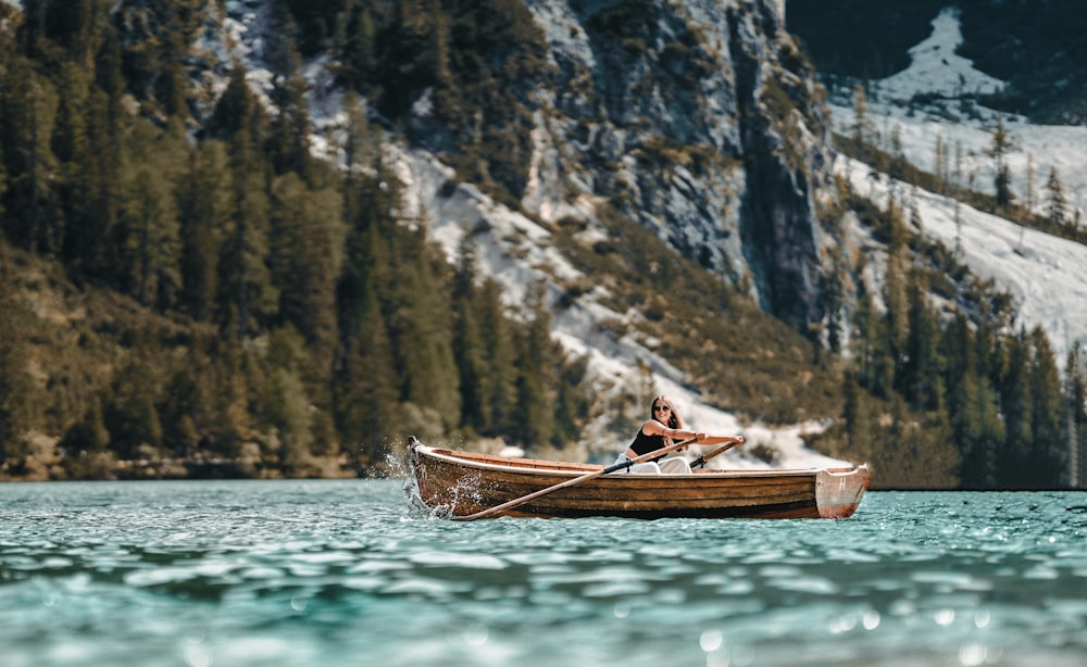 a man in a boat on a lake with mountains in the background