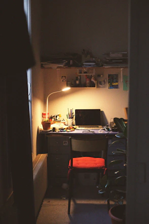 A cozy workspace with tarot cards spread out next to a notebook and pen, bathed in warm evening light.