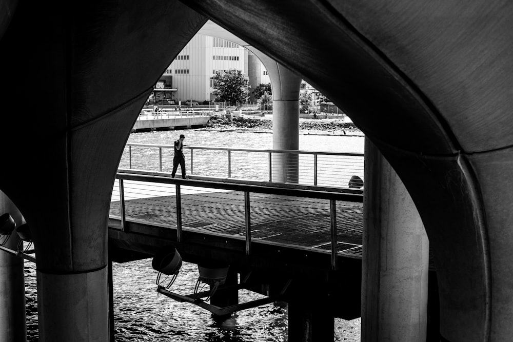 a black and white photo of a person on a bridge