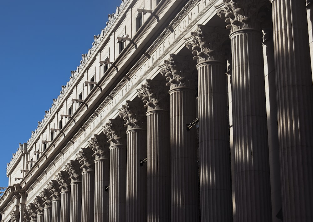 a tall building with columns and a clock on the side of it