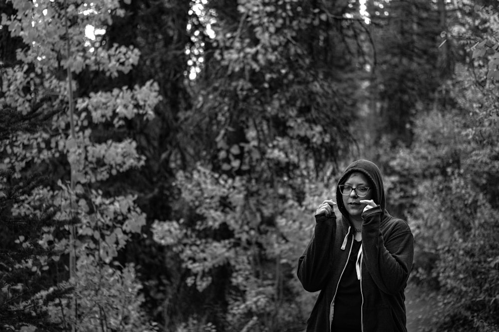 a woman standing in a forest talking on a cell phone