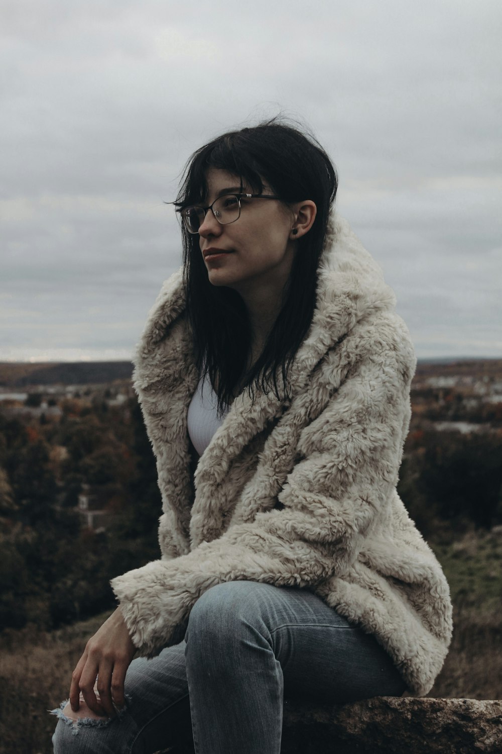 a woman wearing glasses sitting on a rock