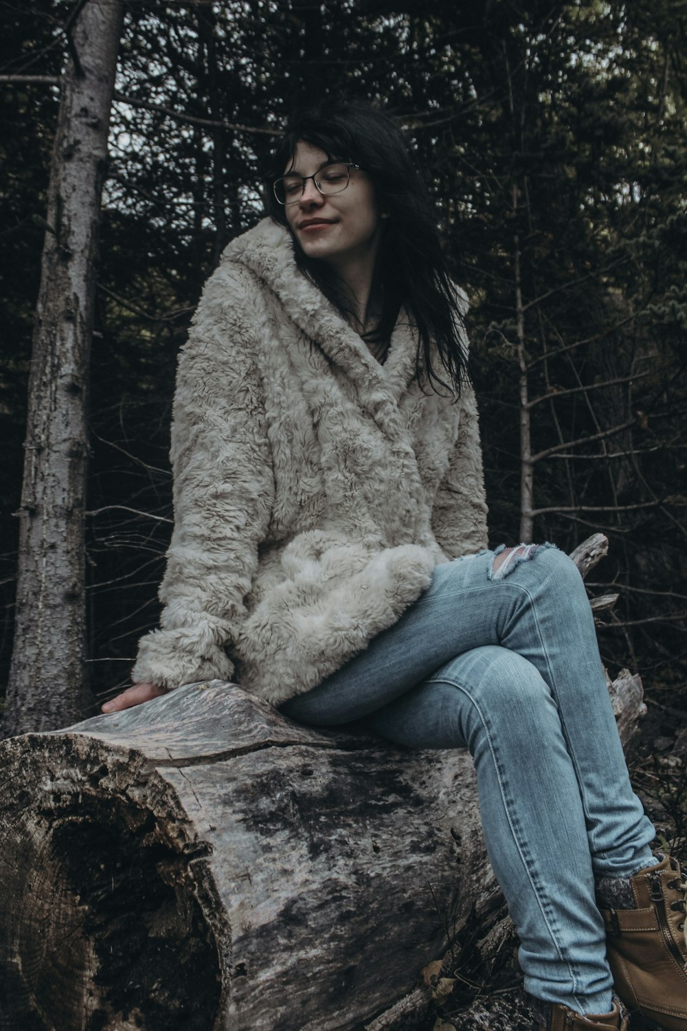 Una mujer sentada en un tronco en el bosque