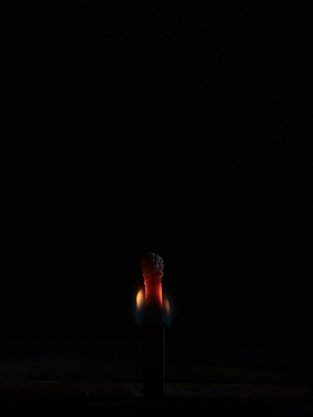 a lit candle in the dark with a black background