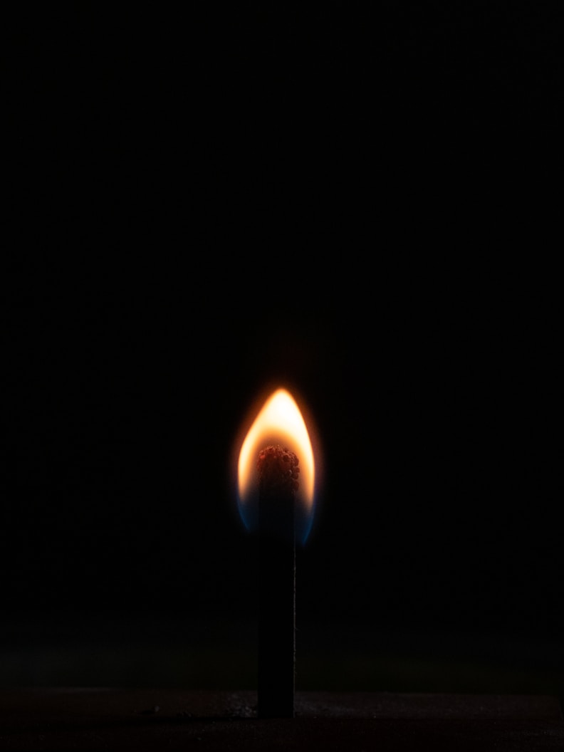 a lit matchstick in the dark with a black background