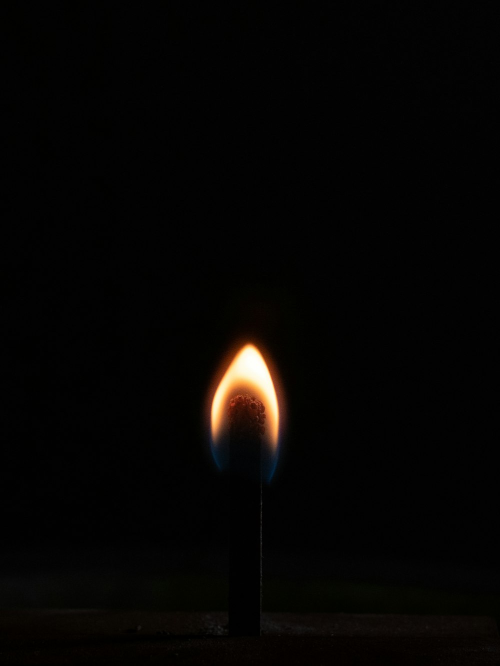 a lit matchstick in the dark with a black background