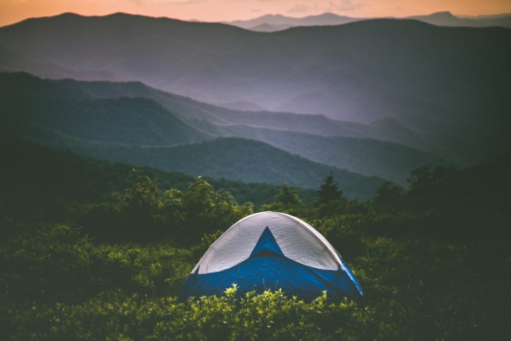 Ein Zelt mitten auf einem Feld mit Bergen im Hintergrund