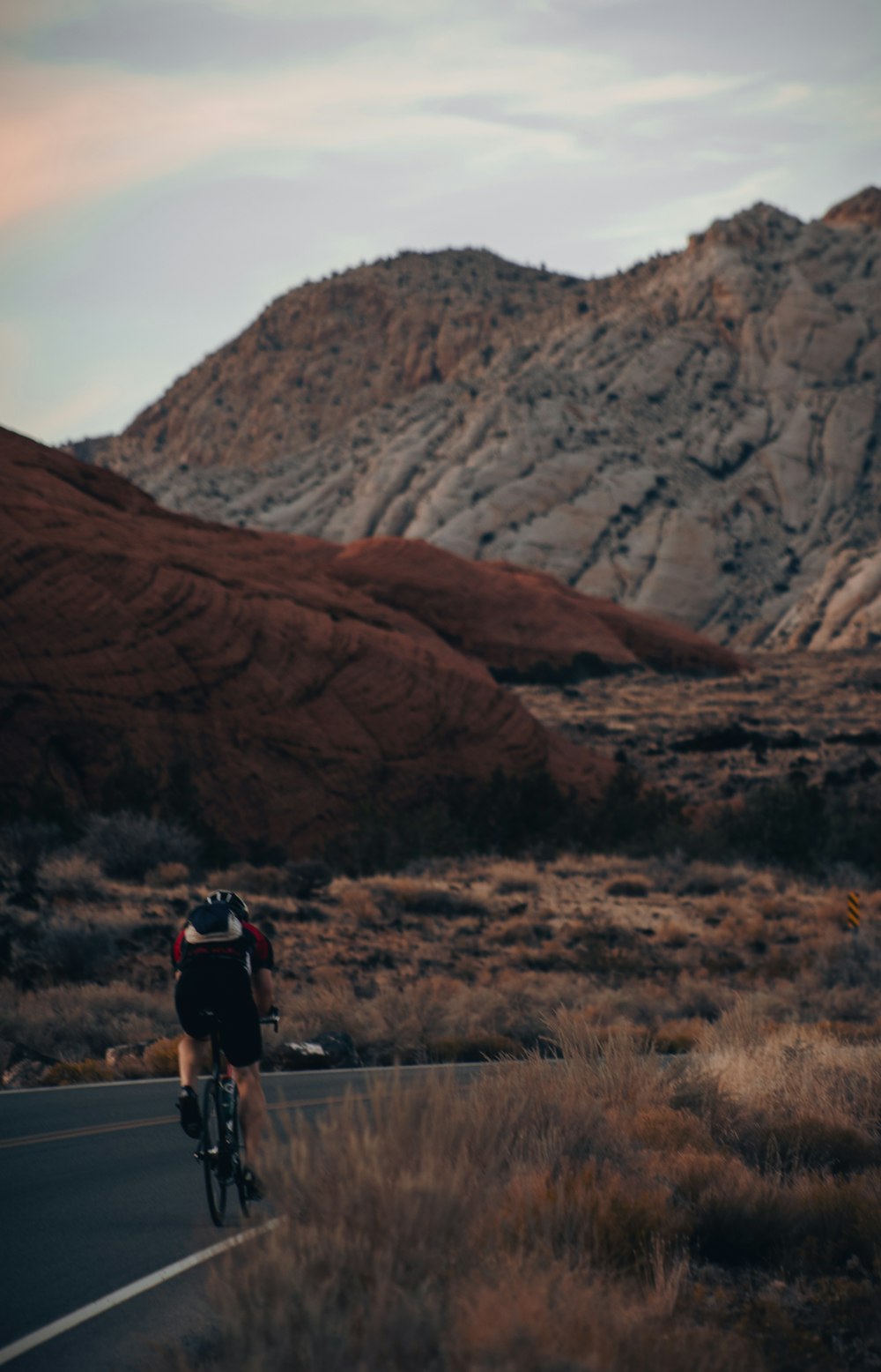 a man riding a bike down a road next to a mountain