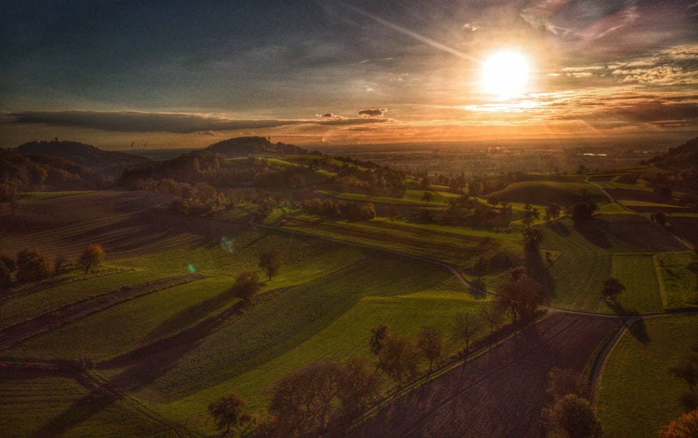 the sun is setting over a green field