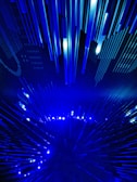 A dynamic and futuristic display featuring numerous elongated blue light beams arranged in a radiating pattern, creating a sense of movement and depth.