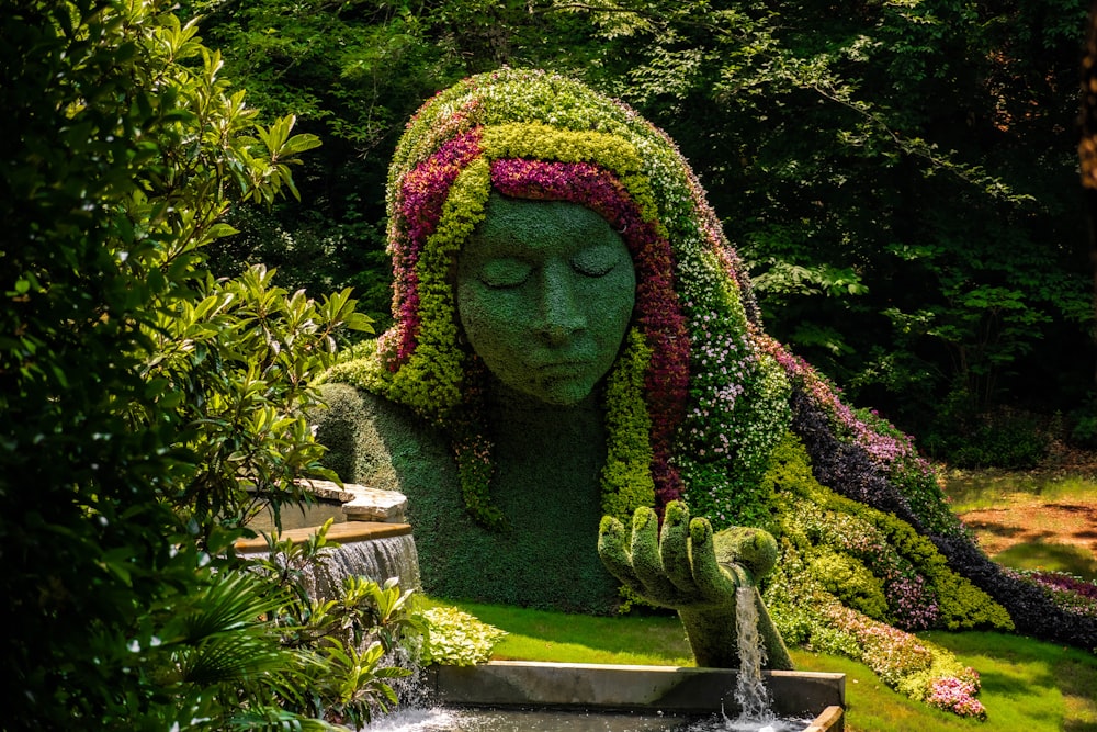 Una estatua de una mujer cubierta de flores en un jardín