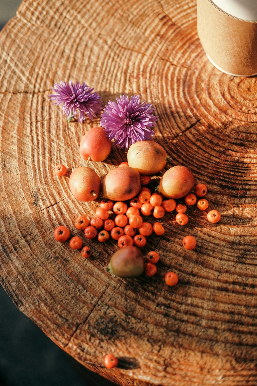 a wooden table topped with purple flowers and fruit