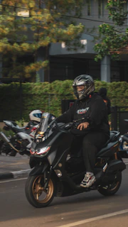 A rider cruising confidently through Nairobi’s bustling streets on a jet black Kenwing scooter