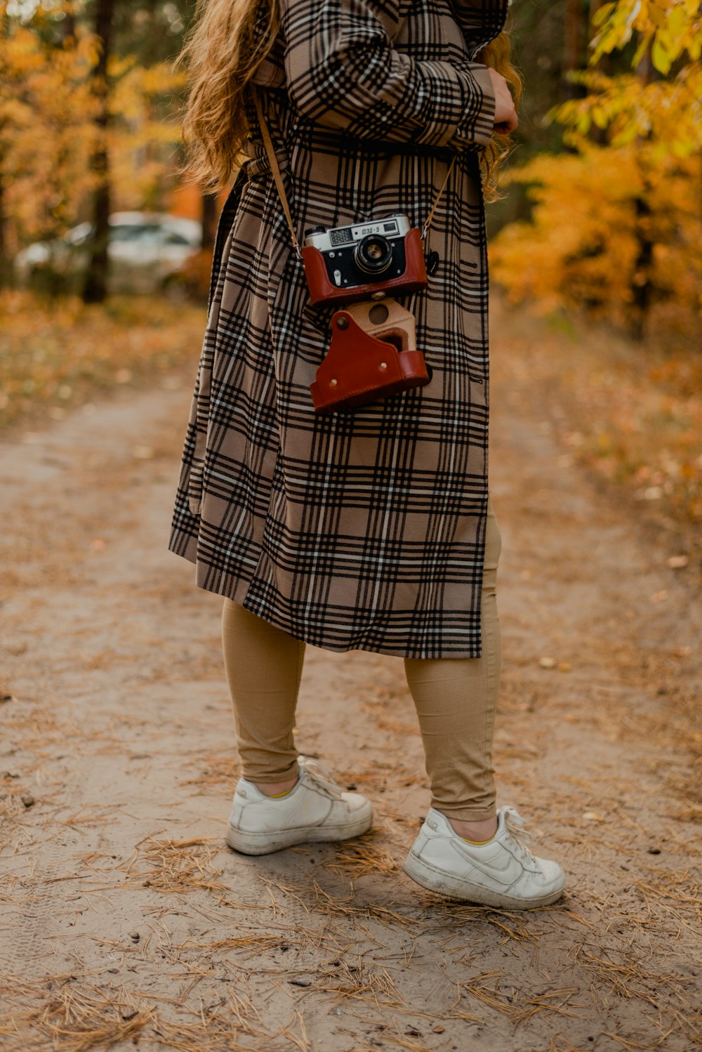 a woman standing on a dirt road holding a camera