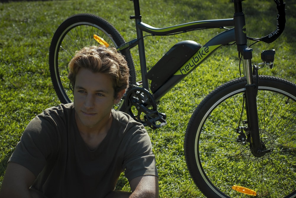 a man sitting in the grass next to a bicycle