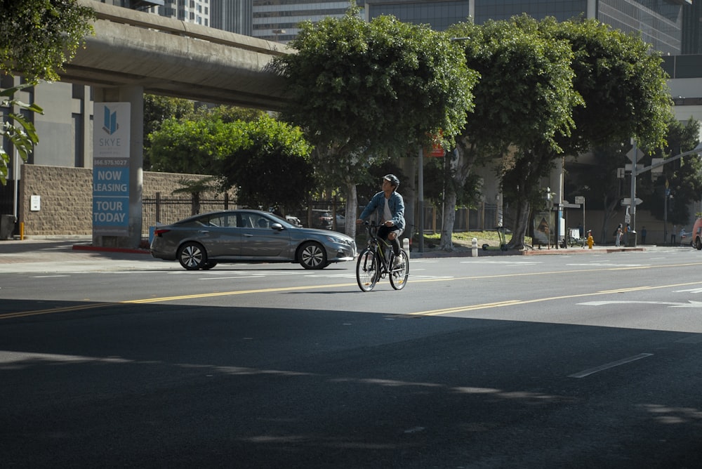 a man riding a bike down a street next to a car