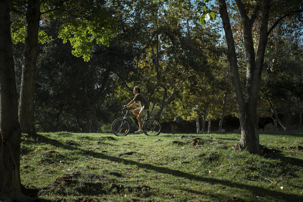 a man riding a bike through a lush green park