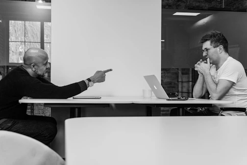 two men sitting at a table with a laptop