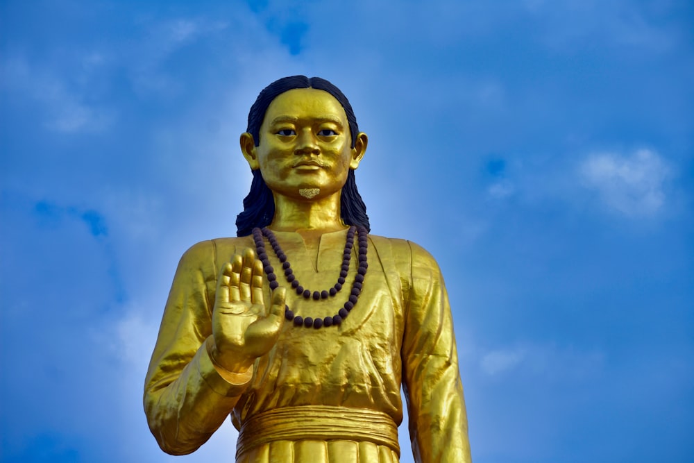 a golden statue of a person with a beaded necklace