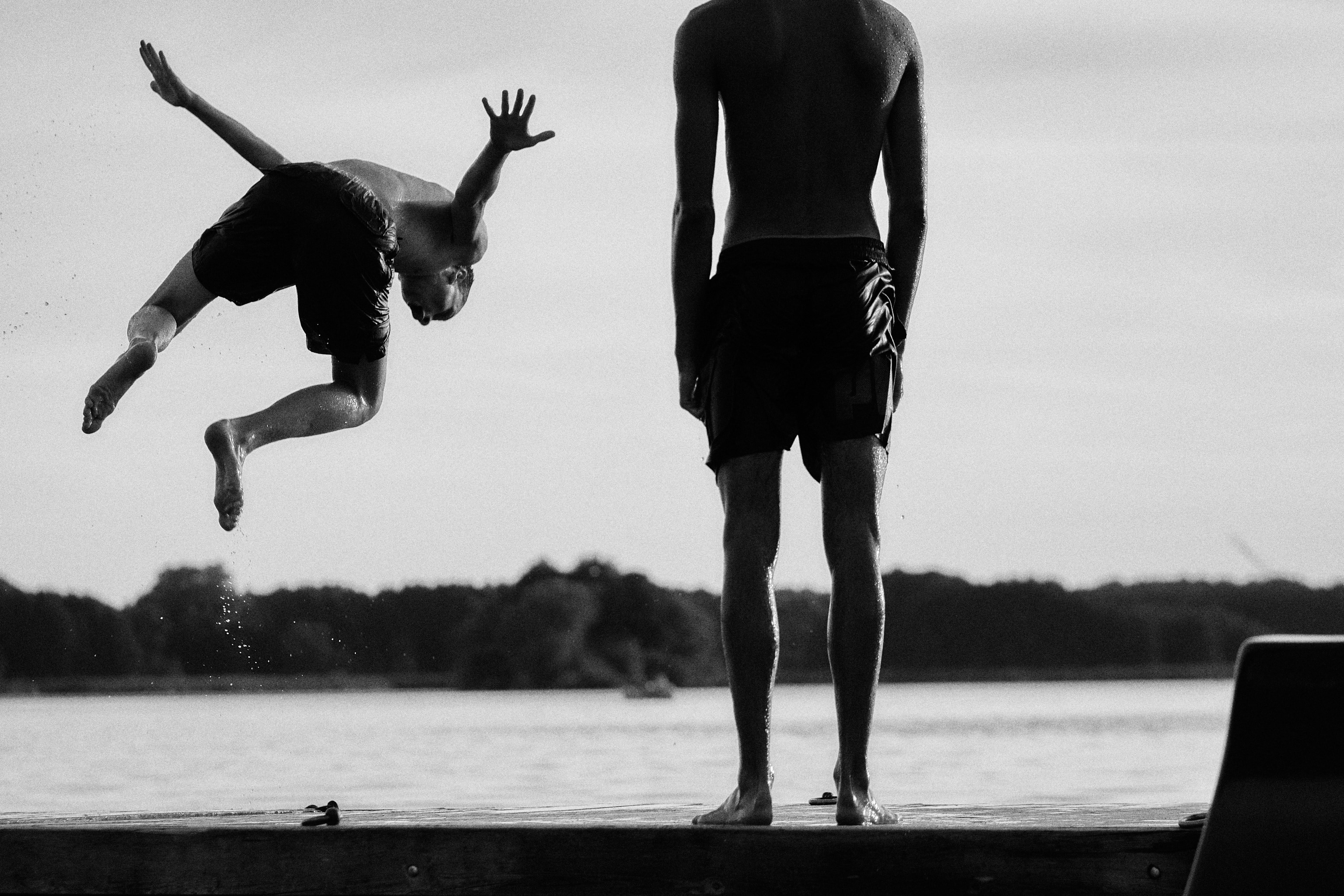 a man jumping off a dock into the water