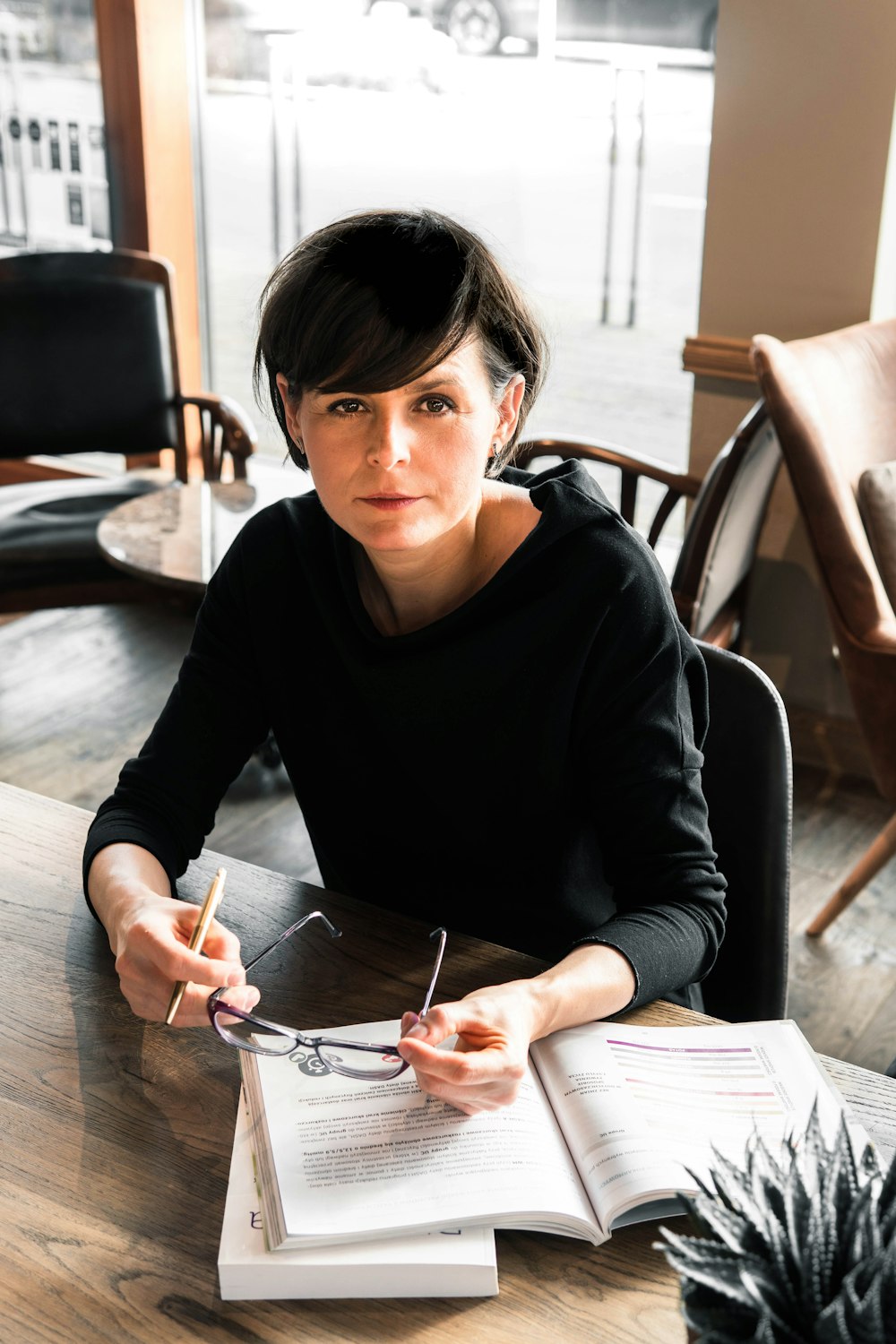 a woman sitting at a table with a book and pen