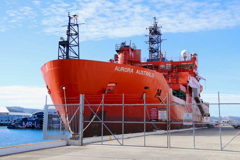 a large orange boat docked at a pier