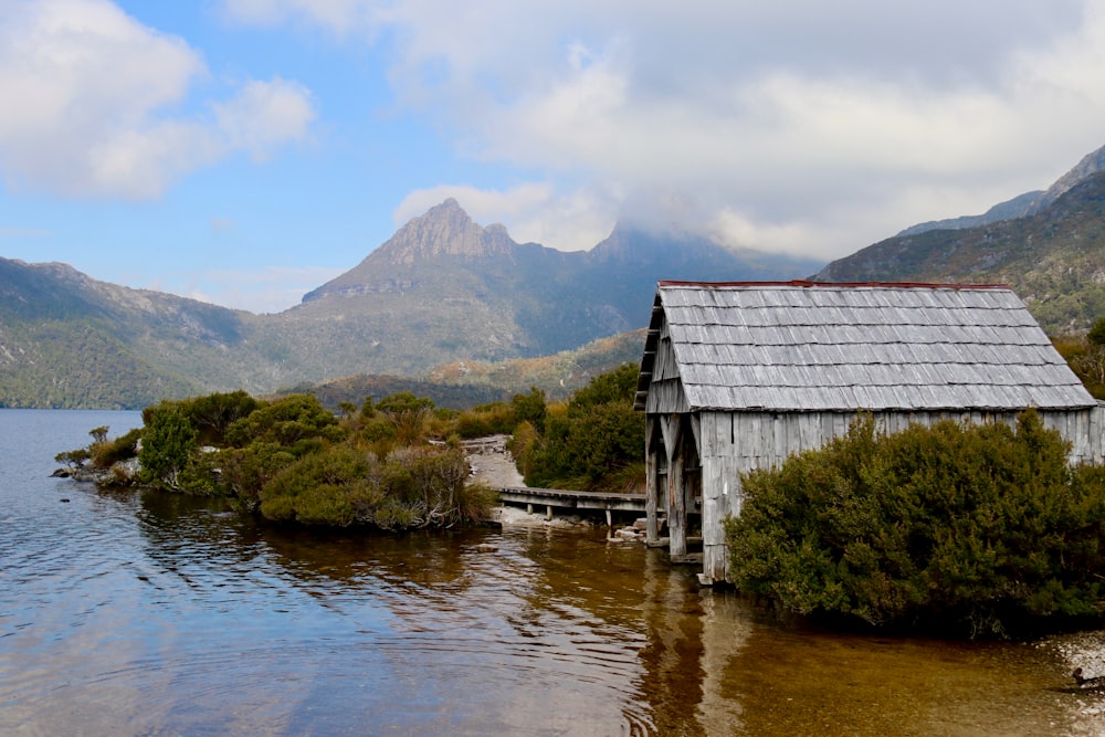 Una casa sentada en la cima de un lago junto a las montañas